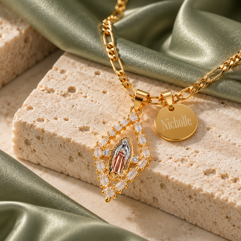 Gold diamond-shaped Virgin Mary pendant with crystal border and engraved name disc on sage fabric