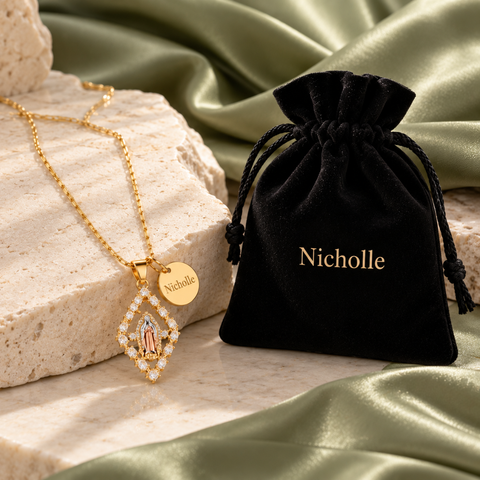 Gold Virgin Mary diamond pendant and name charm beside matching black velvet gift pouch