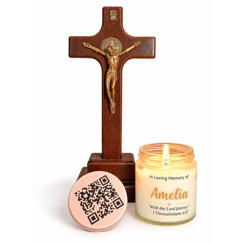 Lit memorial candle with the name Amelia beside a wooden crucifix and a rose-gold lid with a QR code