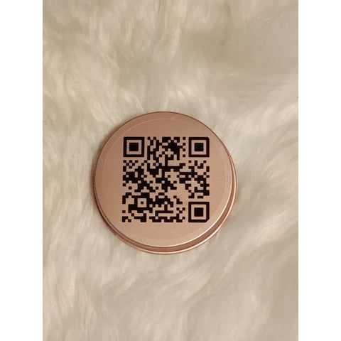 Close-up of a rose-gold candle lid engraved with a QR code